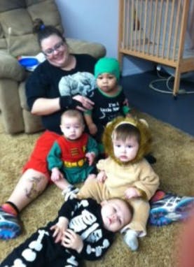 Person sitting on floor with four babies in costumes