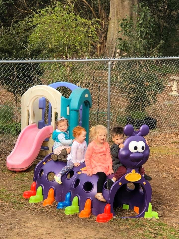 Children playing on a purple caterpillar climber and a small slide
