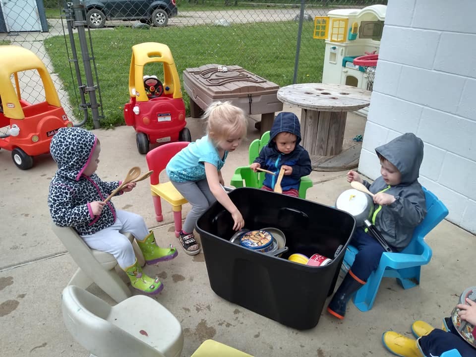 Children playing with items in a large bin outdoors