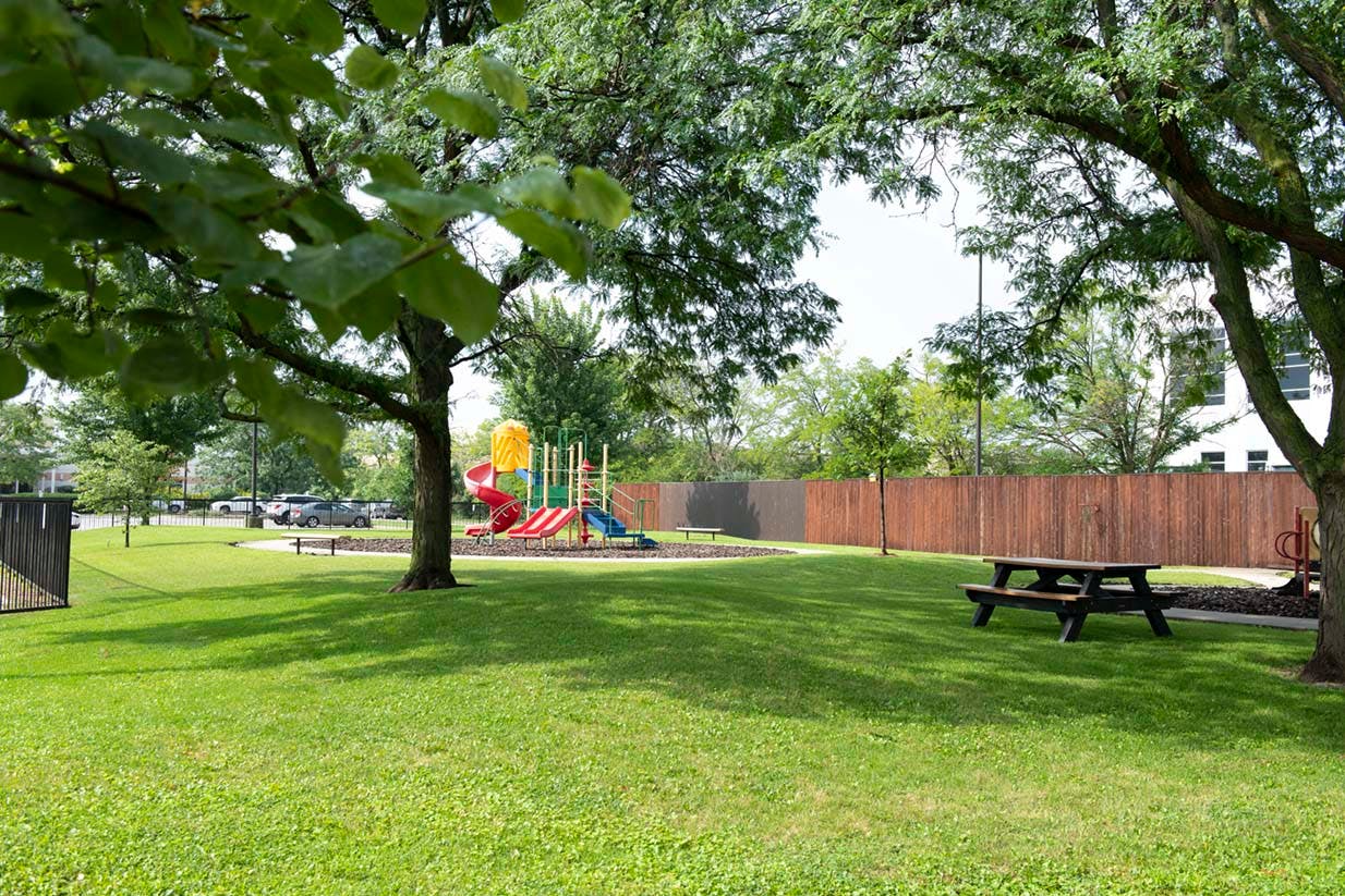Playground with slides and swings, picnic table, and trees