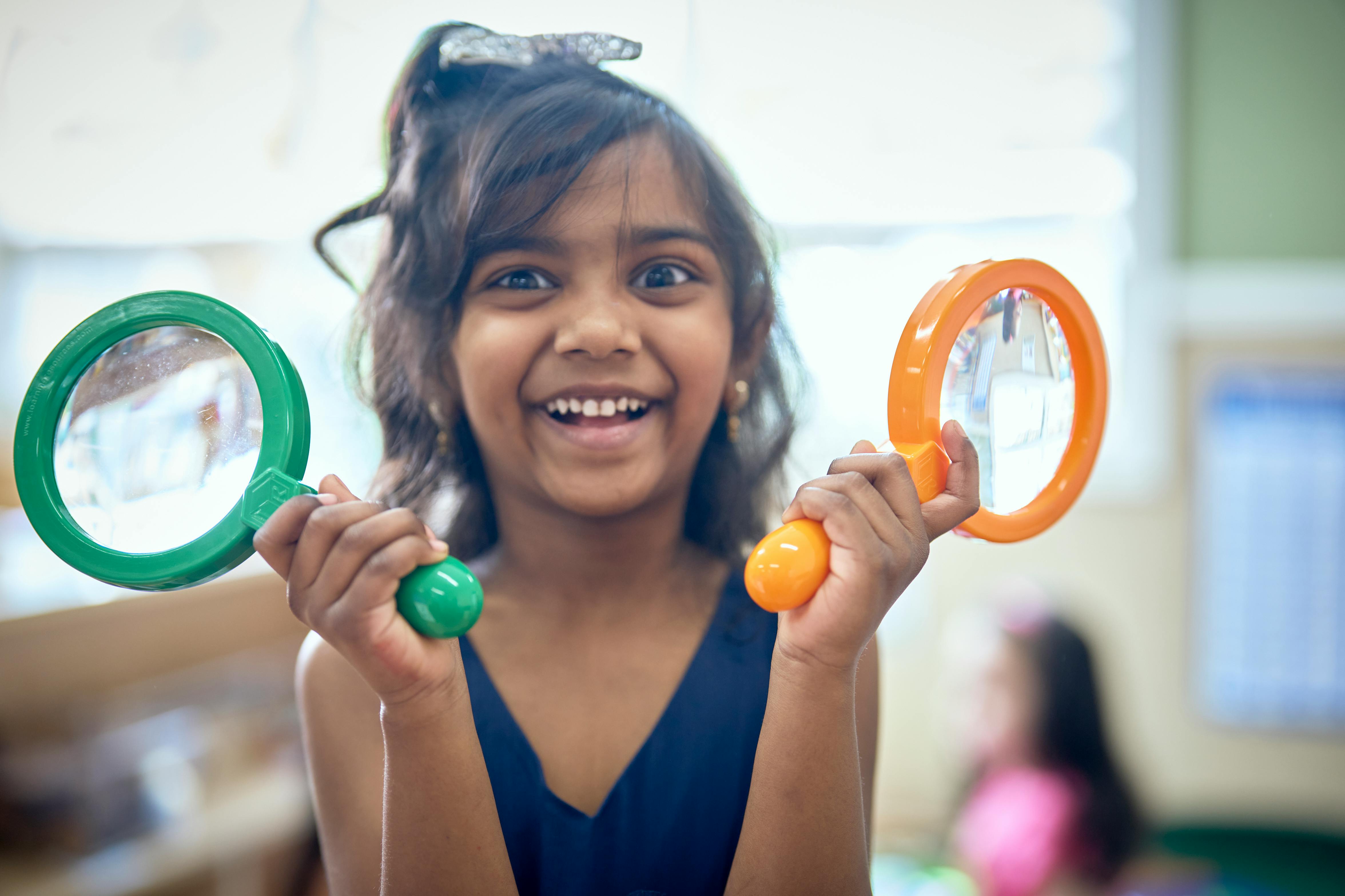 Child holding two magnifying glasses