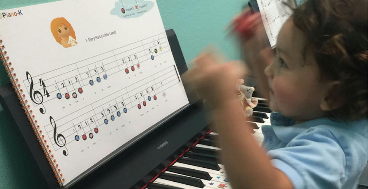 Child playing a piano with sheet music titled Mary Had a Little Lamb