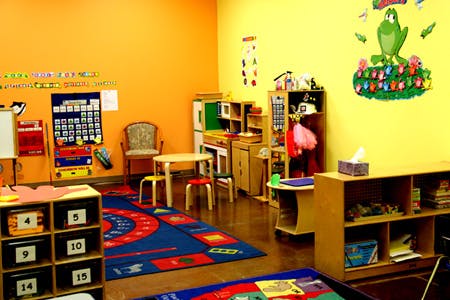 Empty classroom with colorful walls, small tables, chairs, and storage units