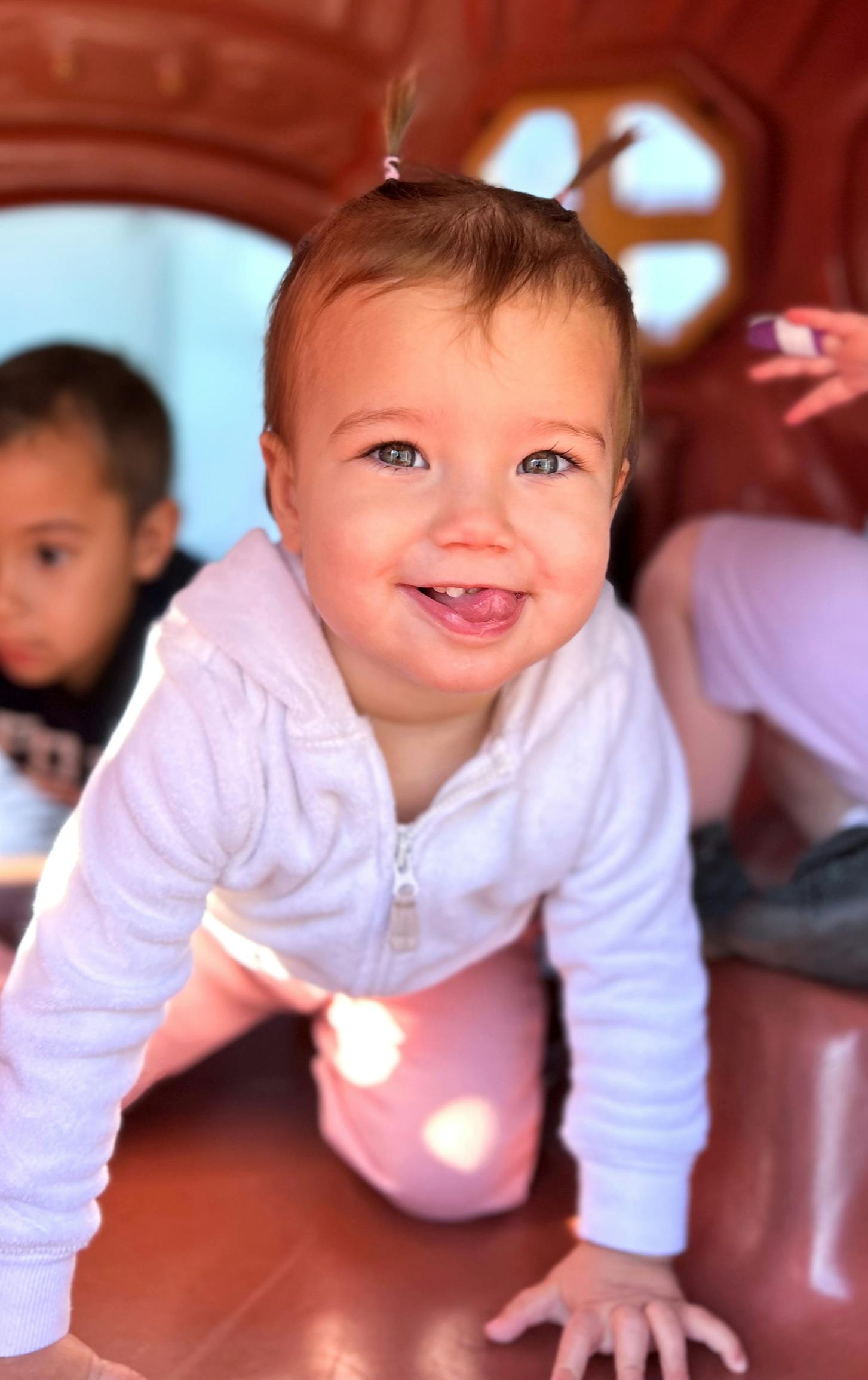 Child on hands and knees smiling and sticking out tongue