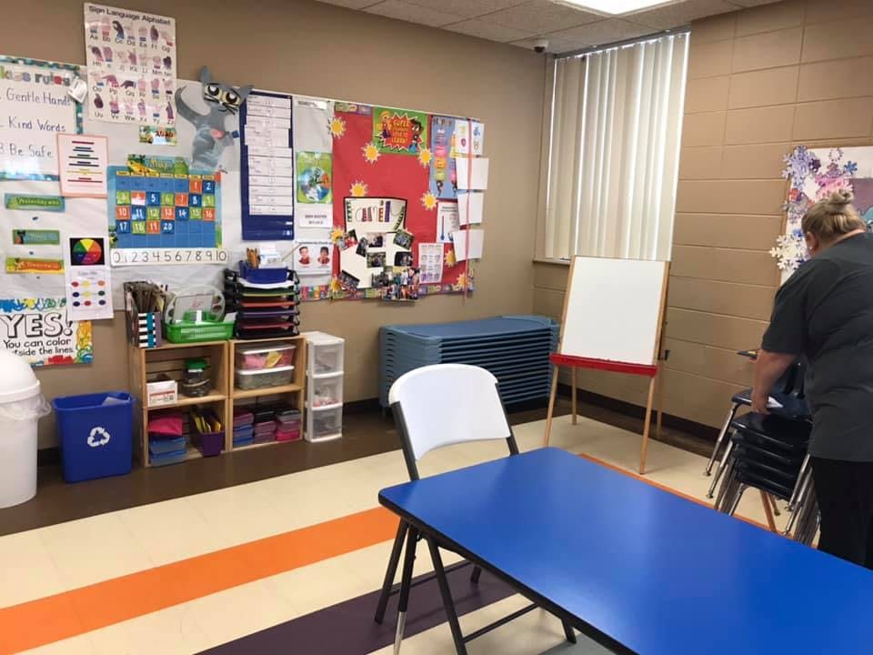 Classroom with bulletin boards, shelves, tables, and a person
