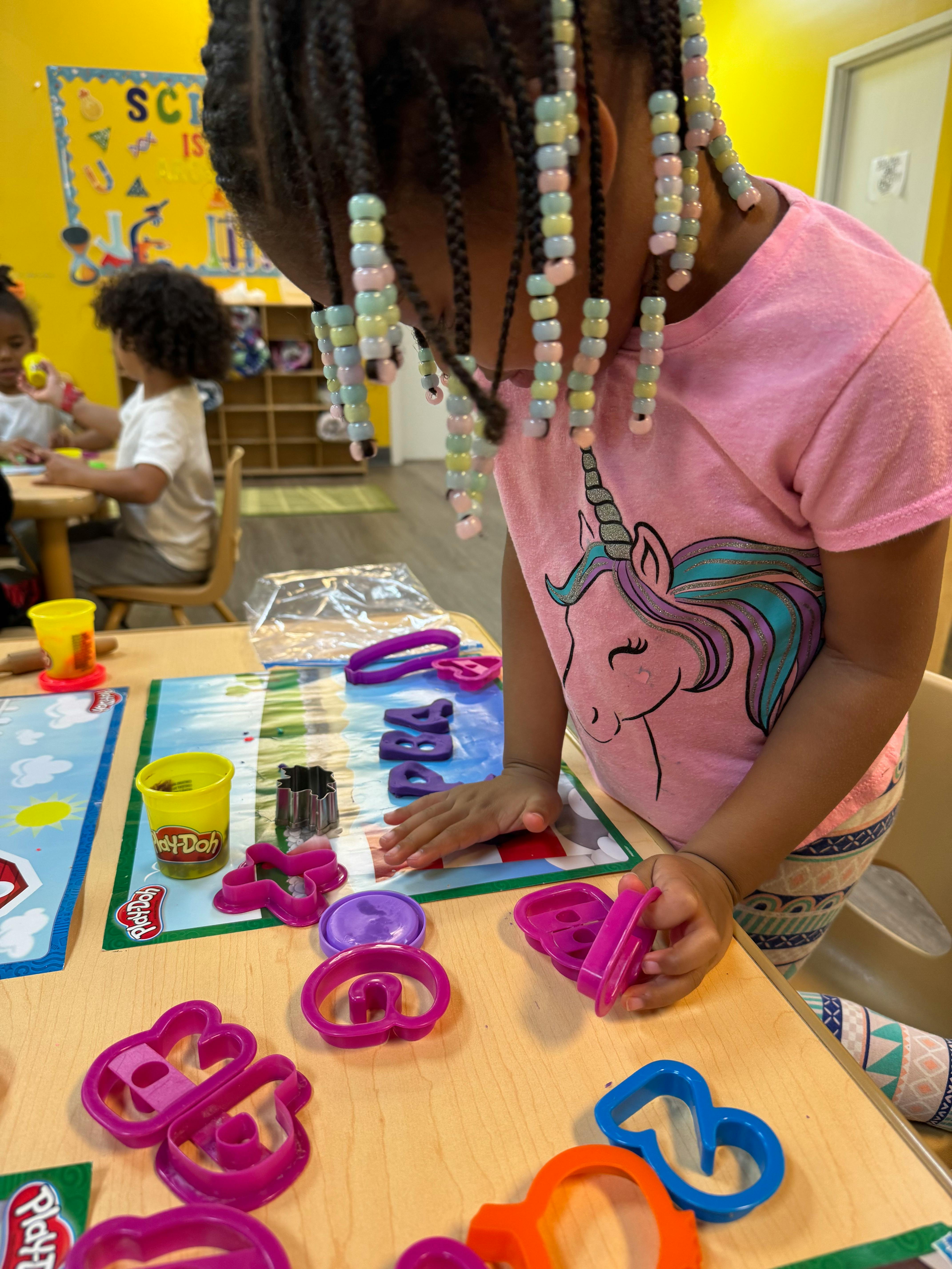 Child playing with Play-Doh and letter cutouts on a table