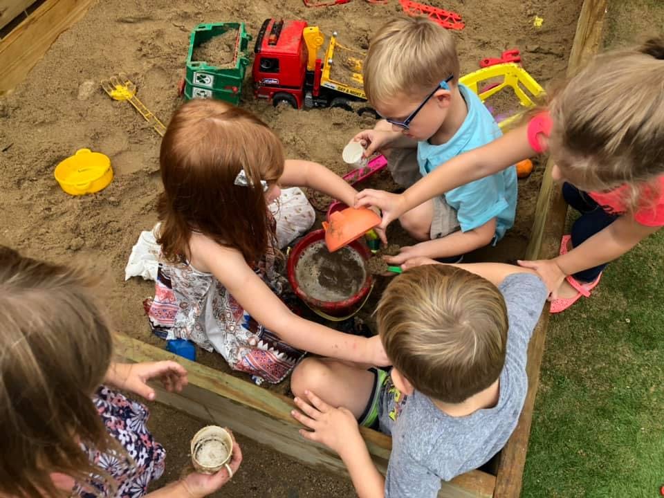 Children playing in a sandbox with toys