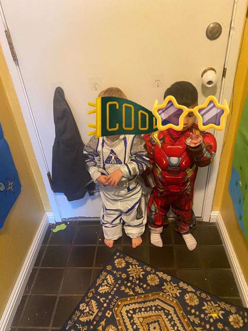 Two children in costumes, one in an astronaut suit and one in a superhero suit