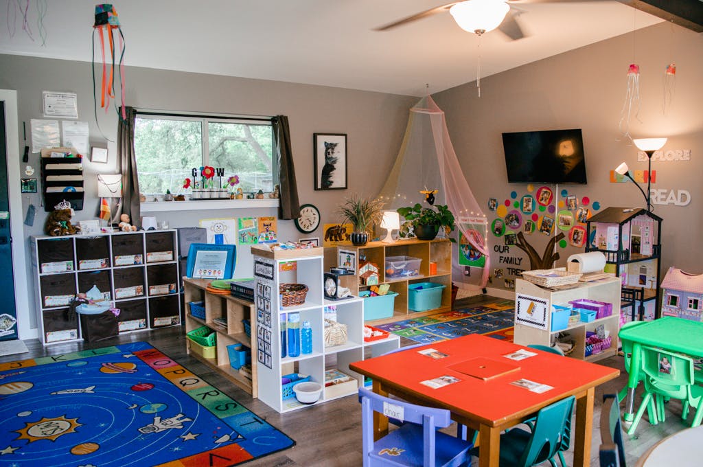 A colorful classroom with tables, chairs, and shelves filled with learning materials