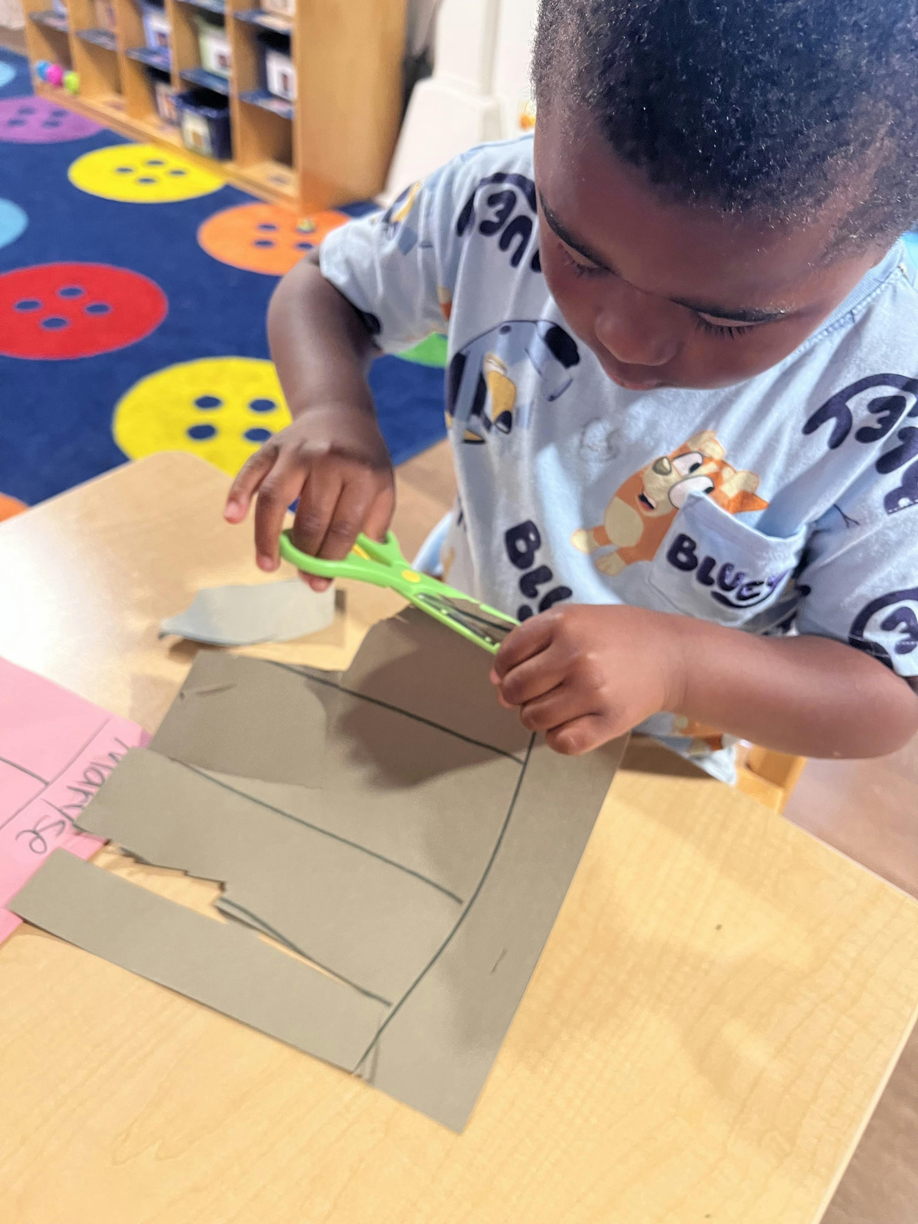 Child cutting cardboard with scissors