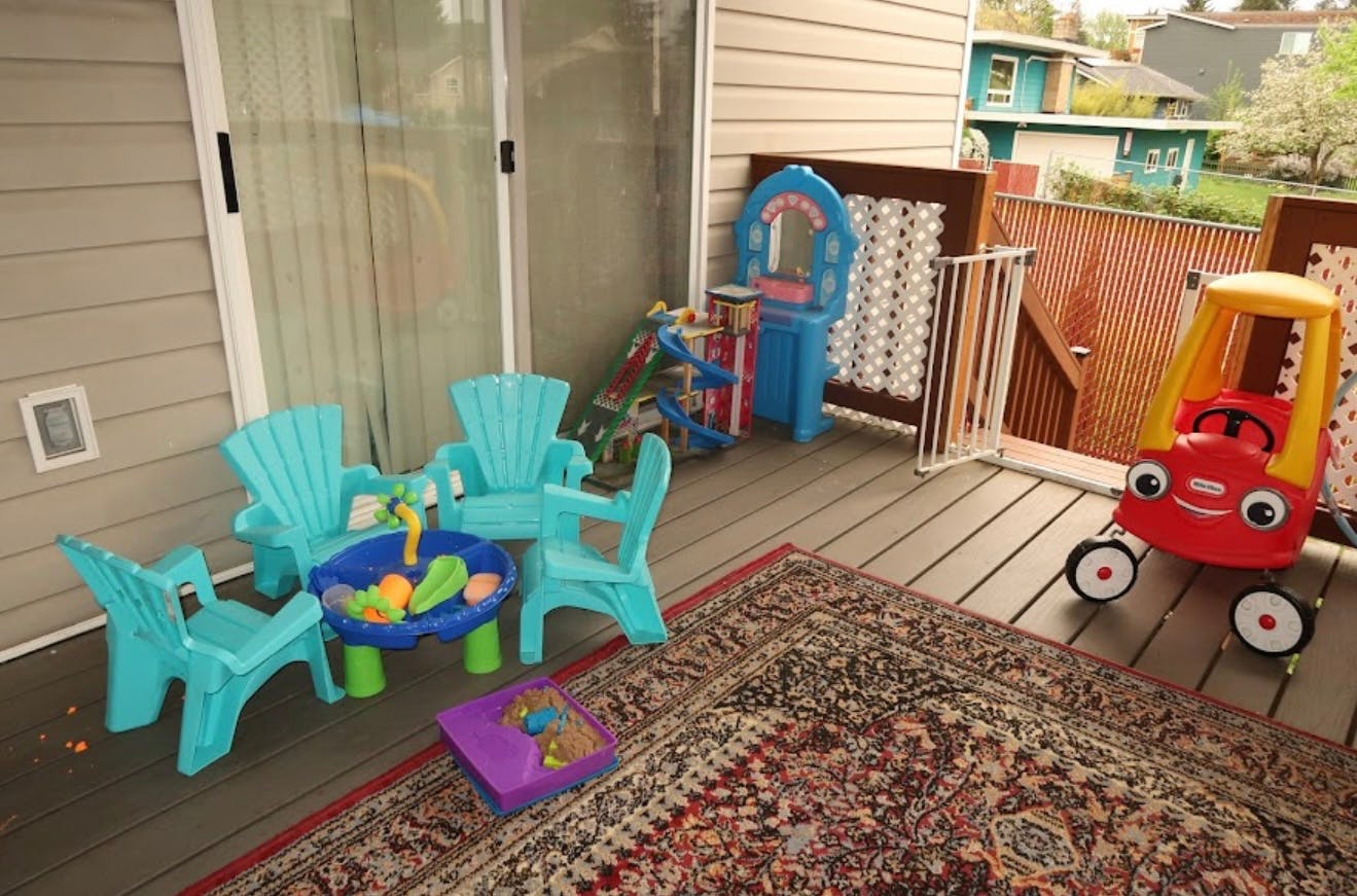 Children's play area on a deck with a table, chairs, and toys