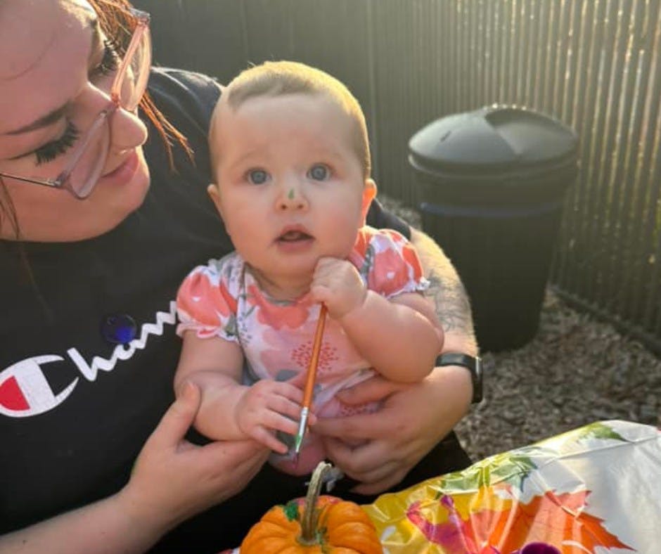 Person holding a child who is holding a paintbrush
