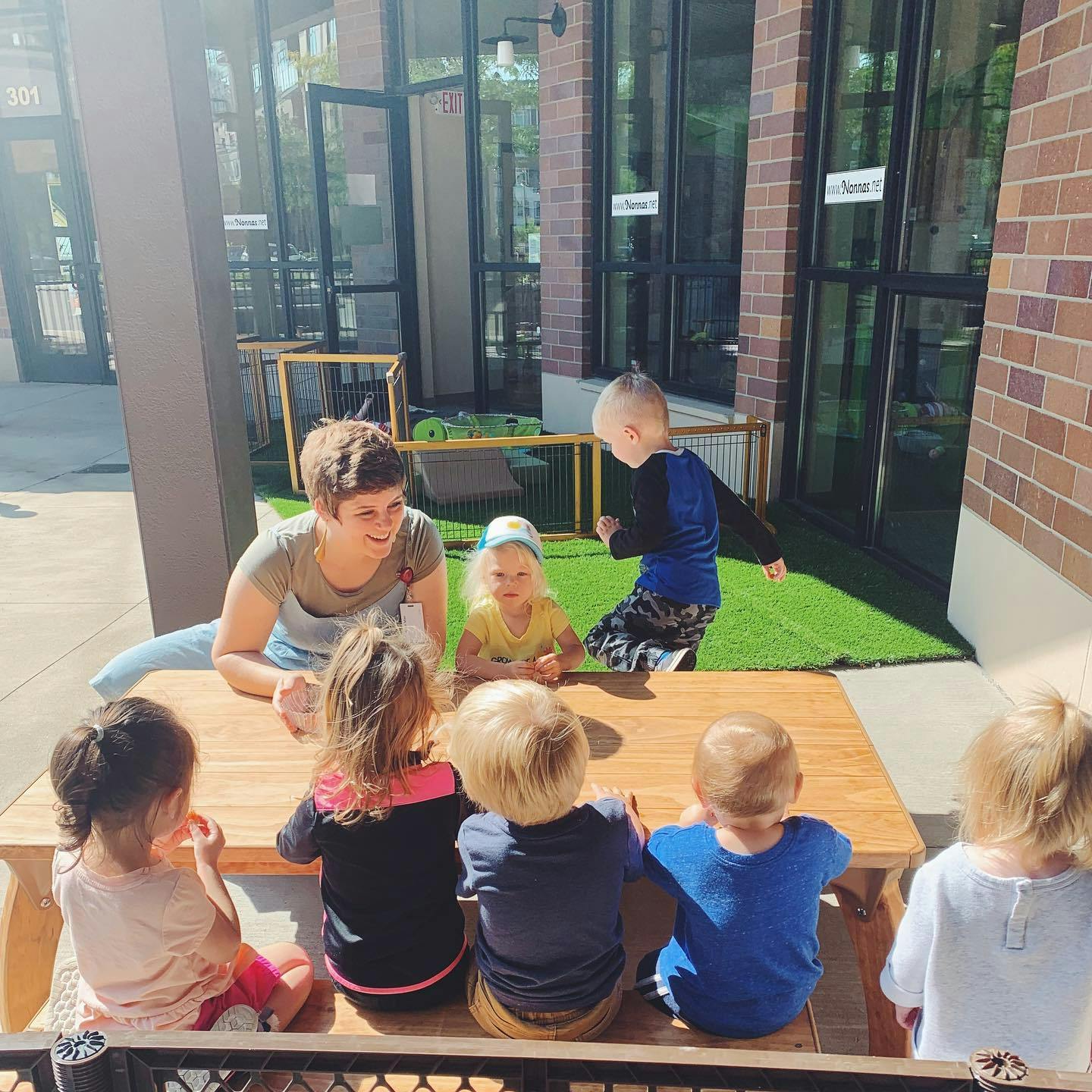 Person interacting with children at a table outdoors