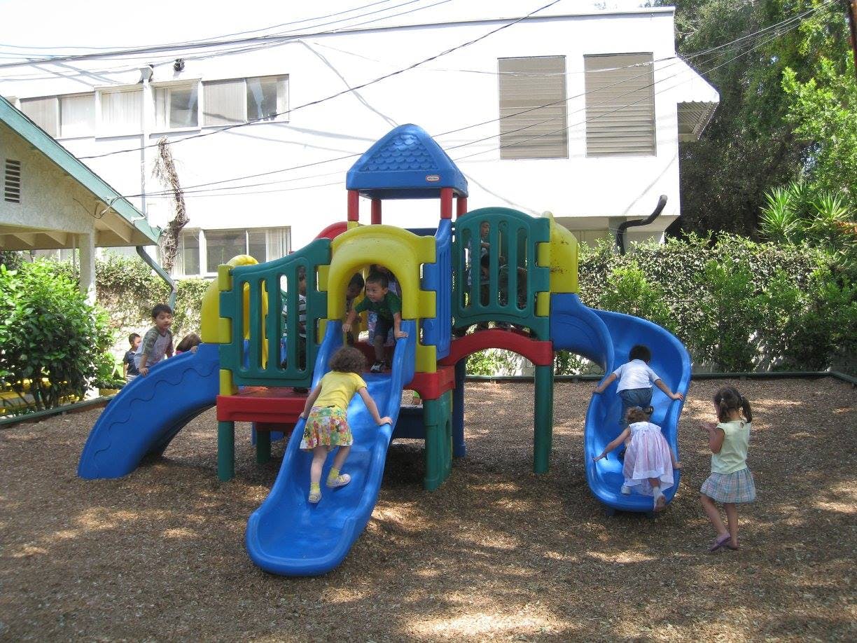 Children playing on a colorful playground structure with slides