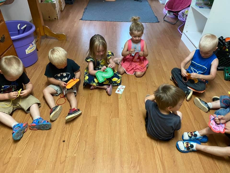 Children sitting on a wooden floor playing with toys