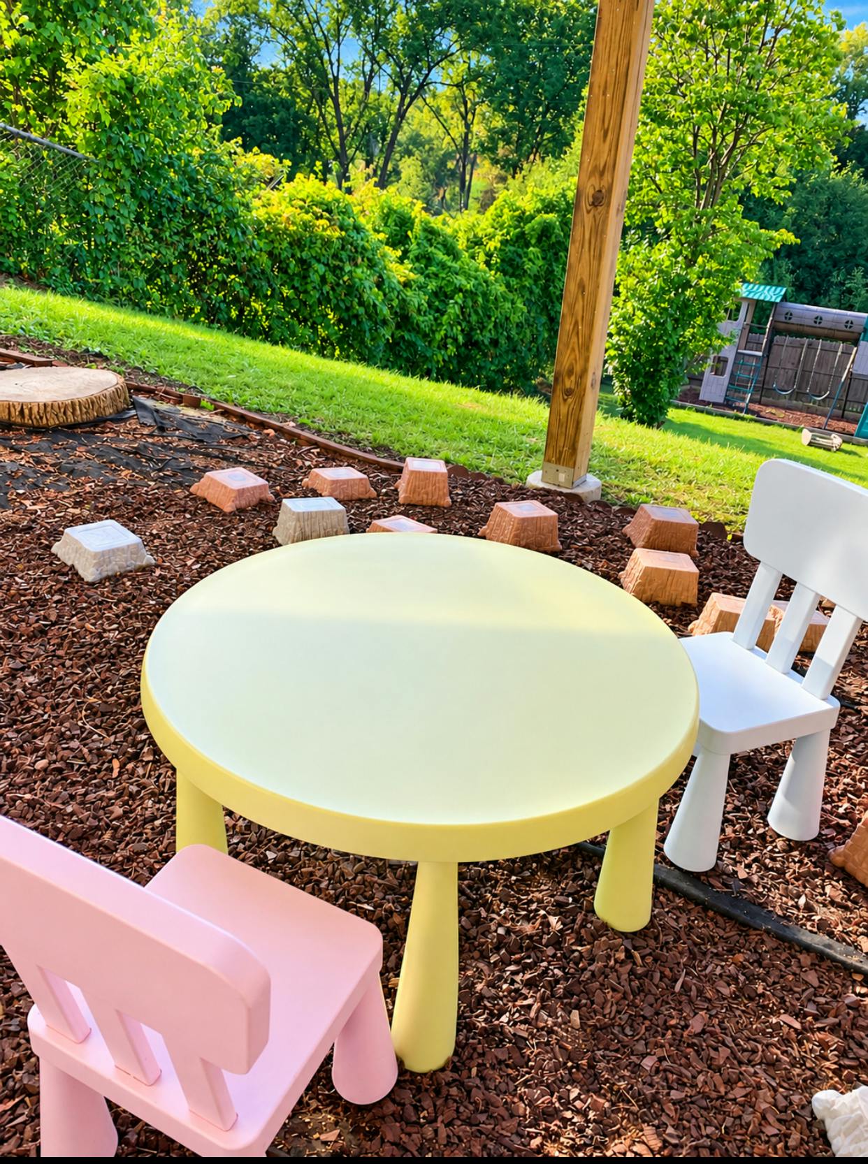 Small round table and chairs on a wood chip outdoor play area