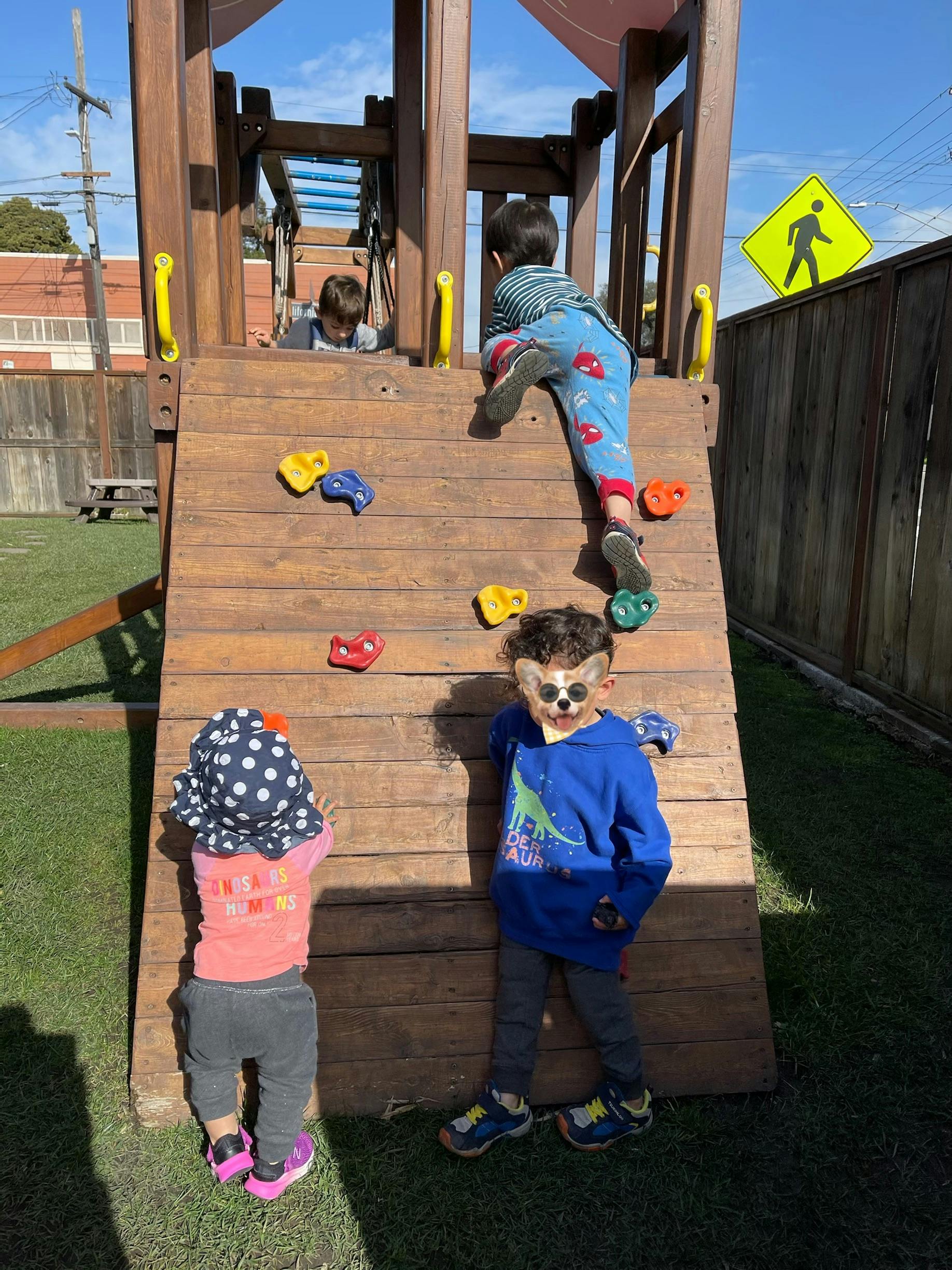 Children playing on a wooden climbing structure with handholds