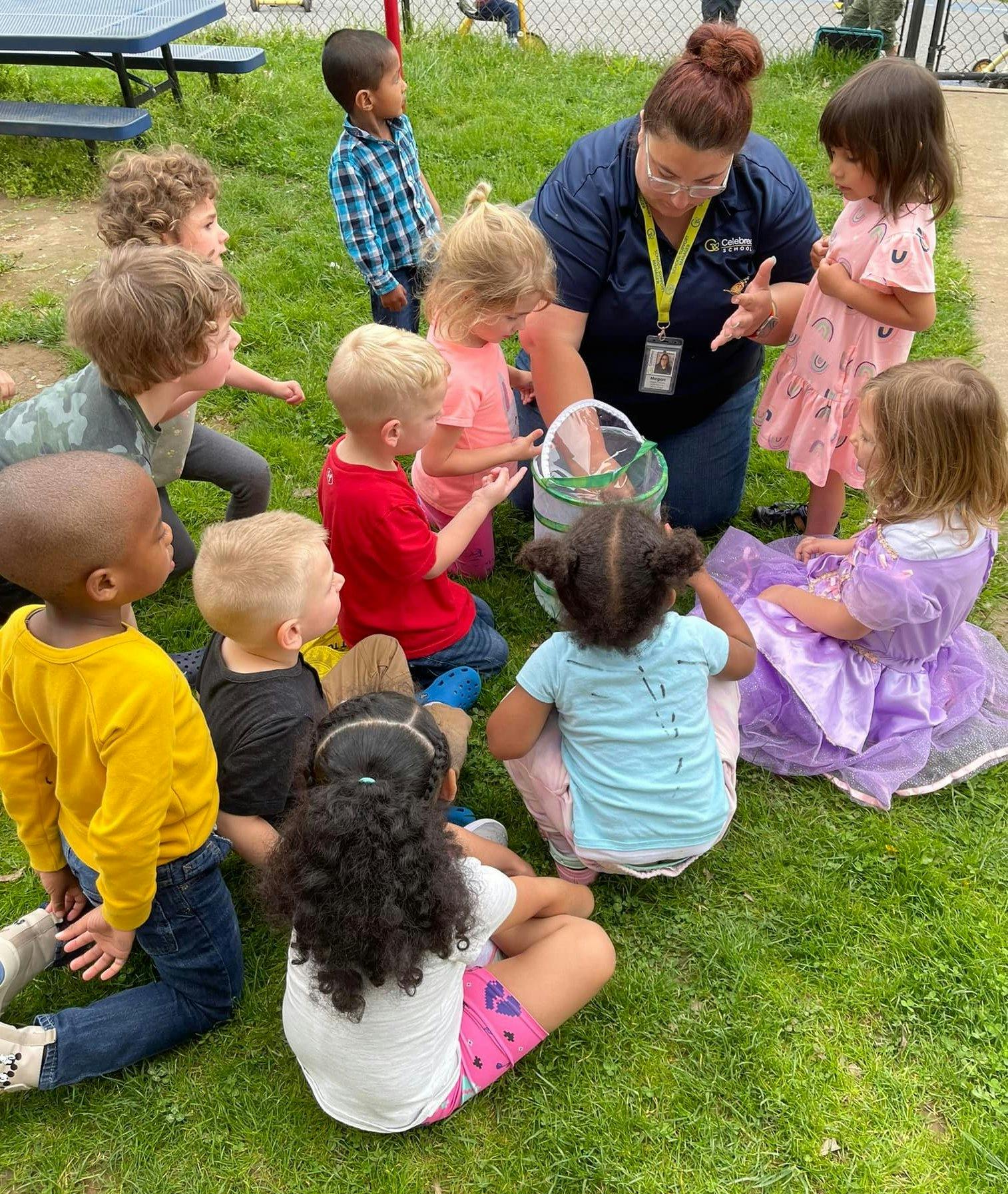 Adult and children gathered around a container on grass