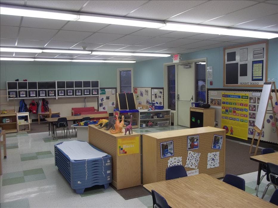 An empty classroom with desks, chairs, storage cubbies, and a calendar