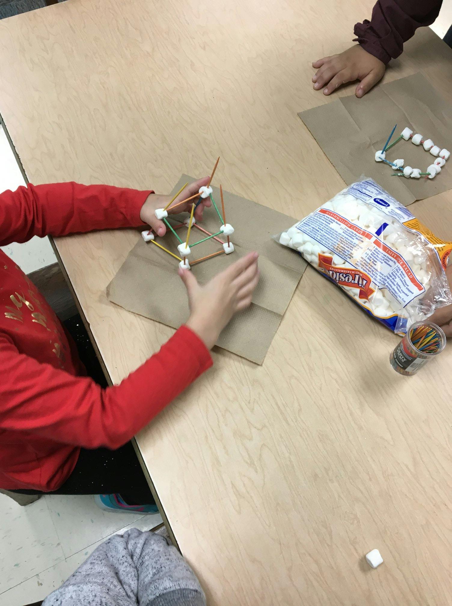 Child building a structure with marshmallows and toothpicks