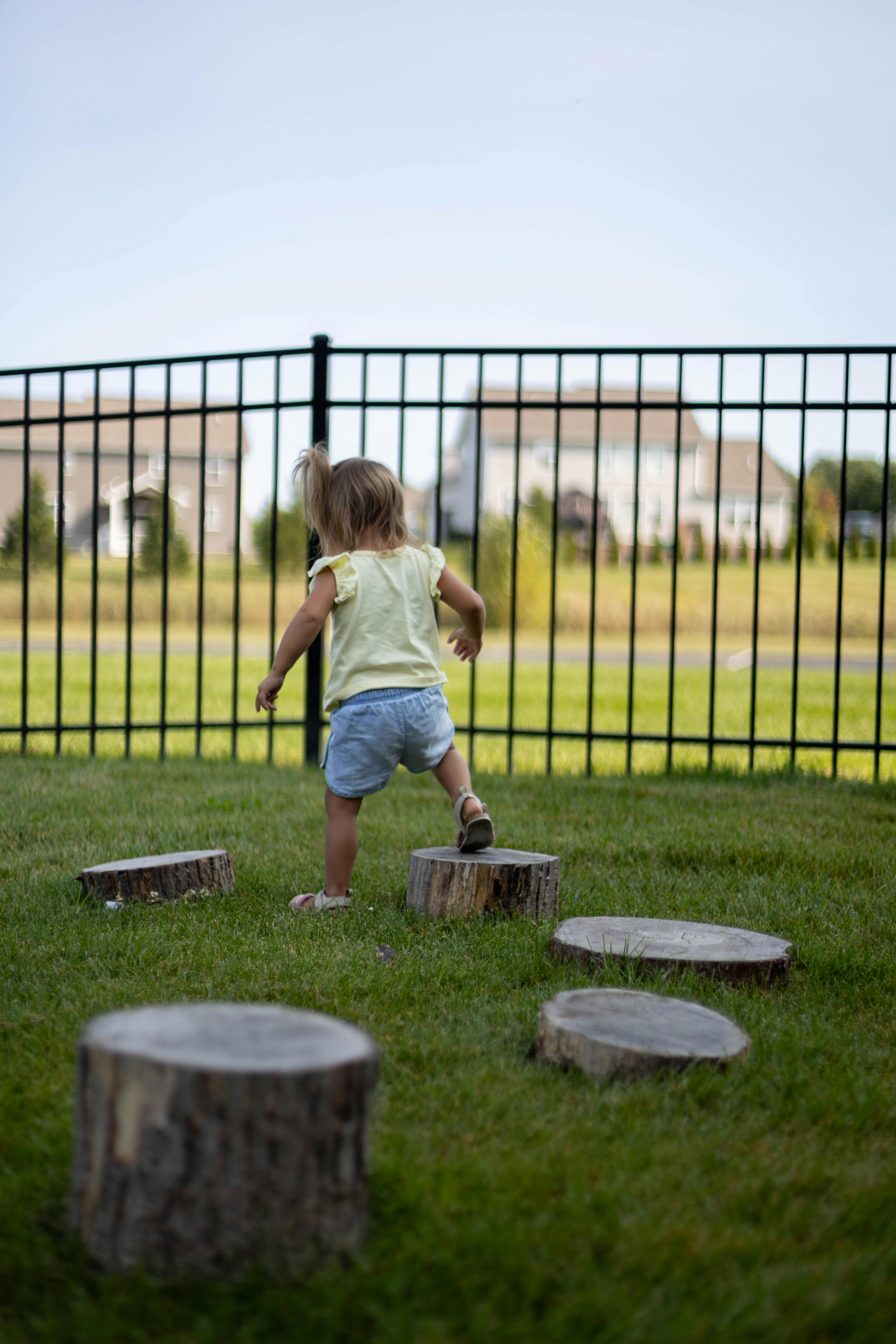 Child stepping on tree stumps in grass