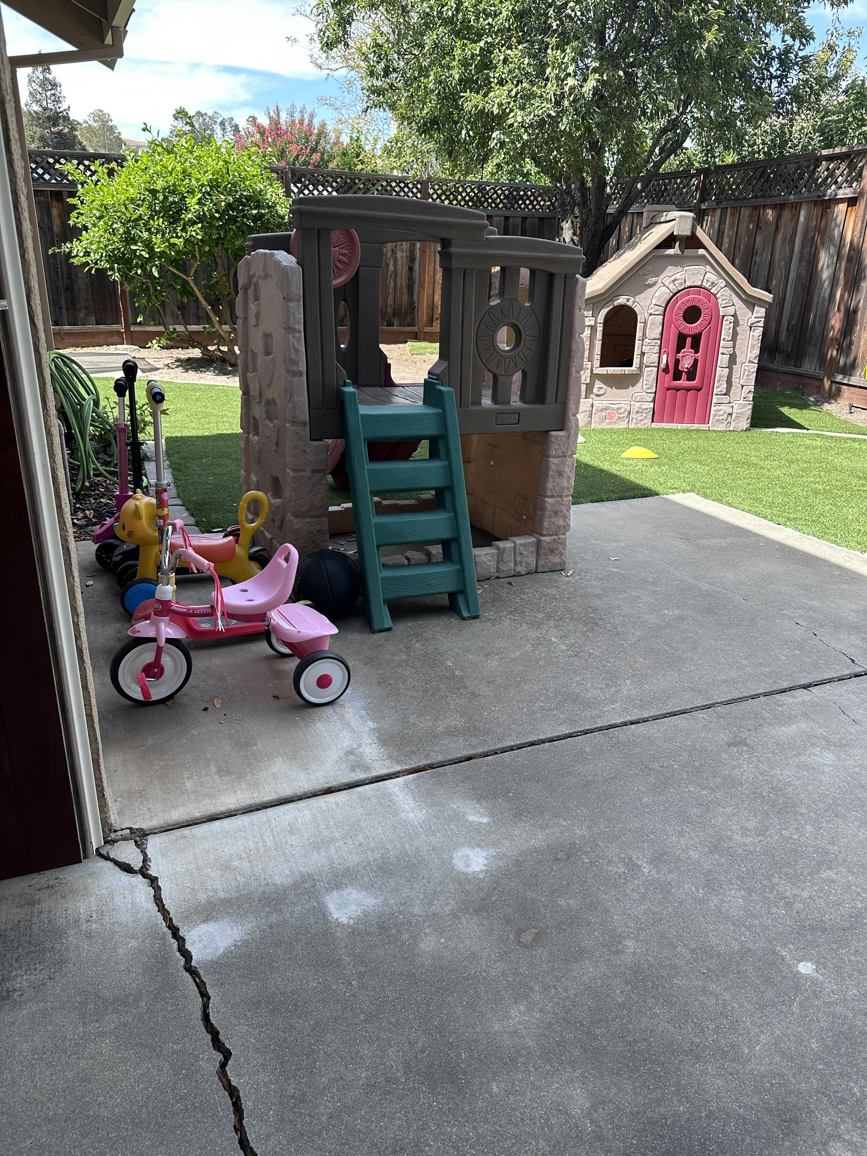 Plastic play structures and ride-on toys in a backyard