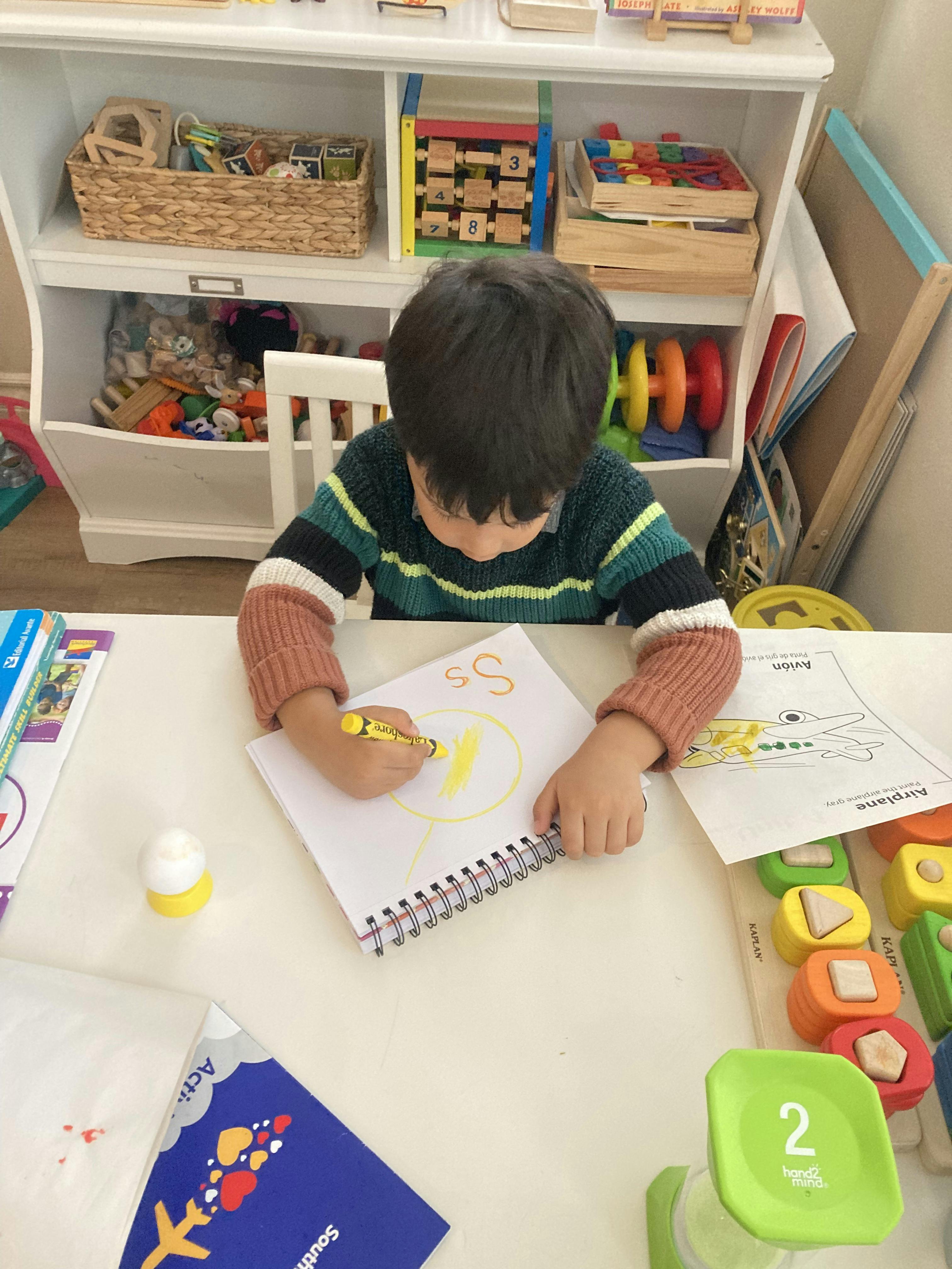 Child coloring in a notebook at a table