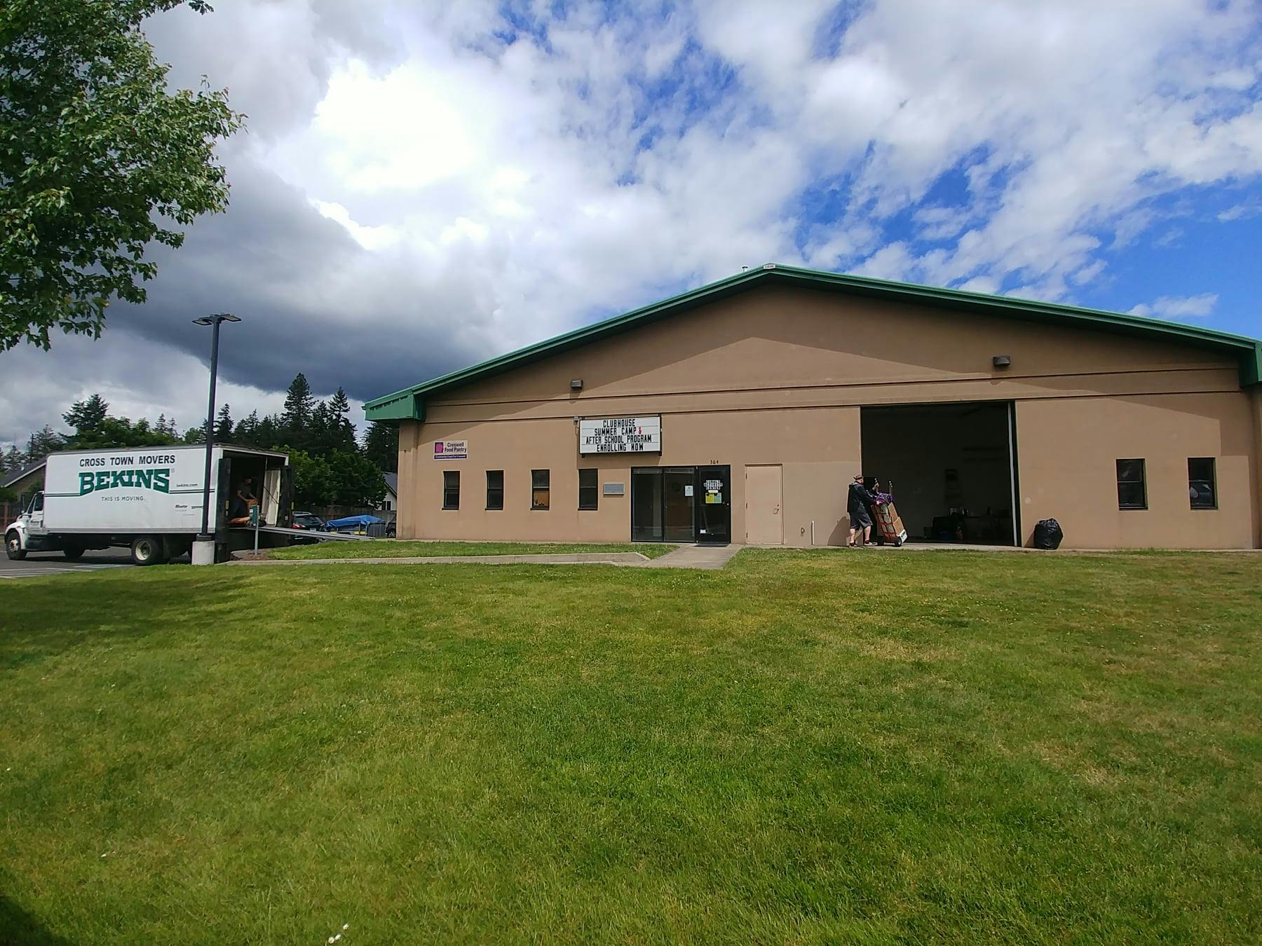 Building with a large open bay door and a moving truck parked nearby