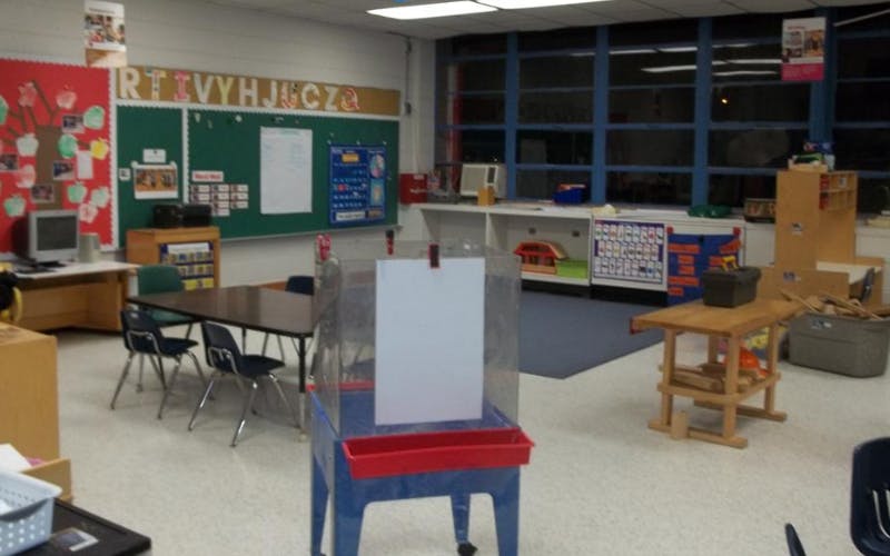 Empty classroom with tables, chairs, and learning displays