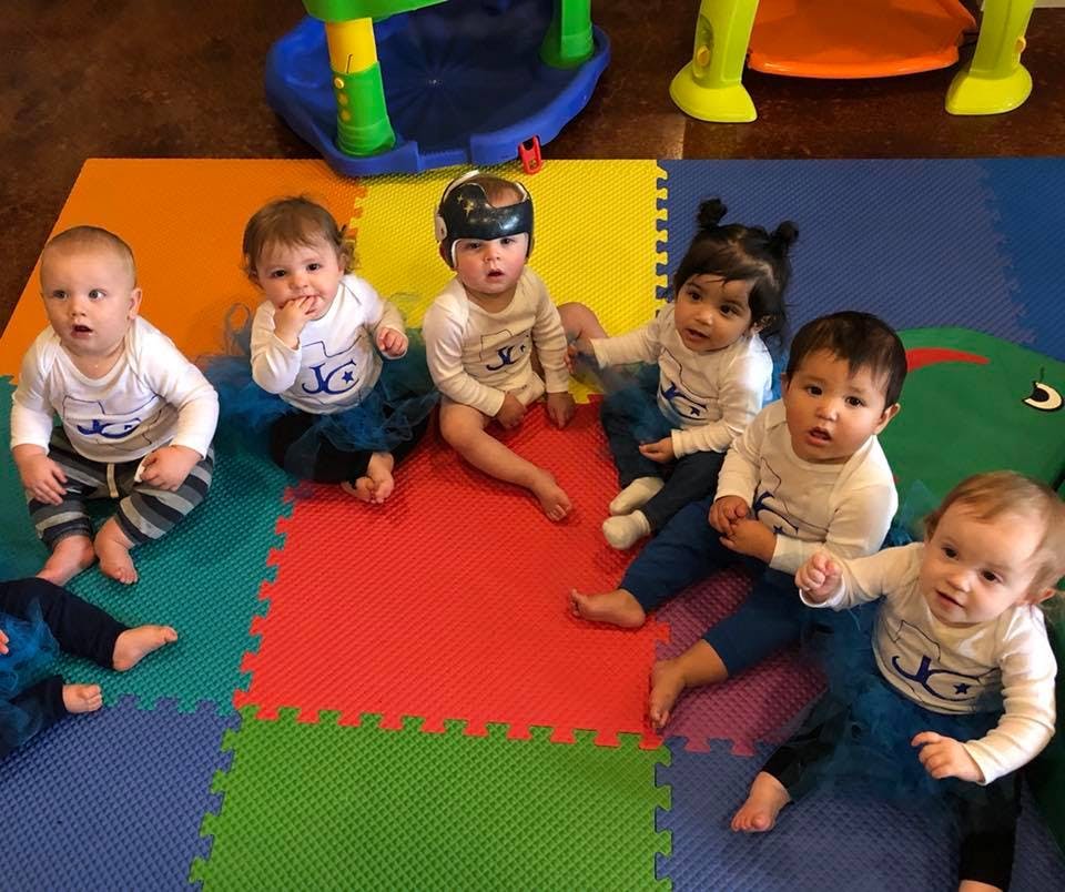 Multiple babies sitting on a colorful playmat