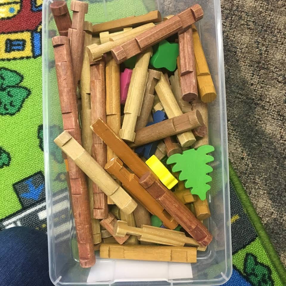 Plastic bin filled with wooden building blocks and colorful shapes