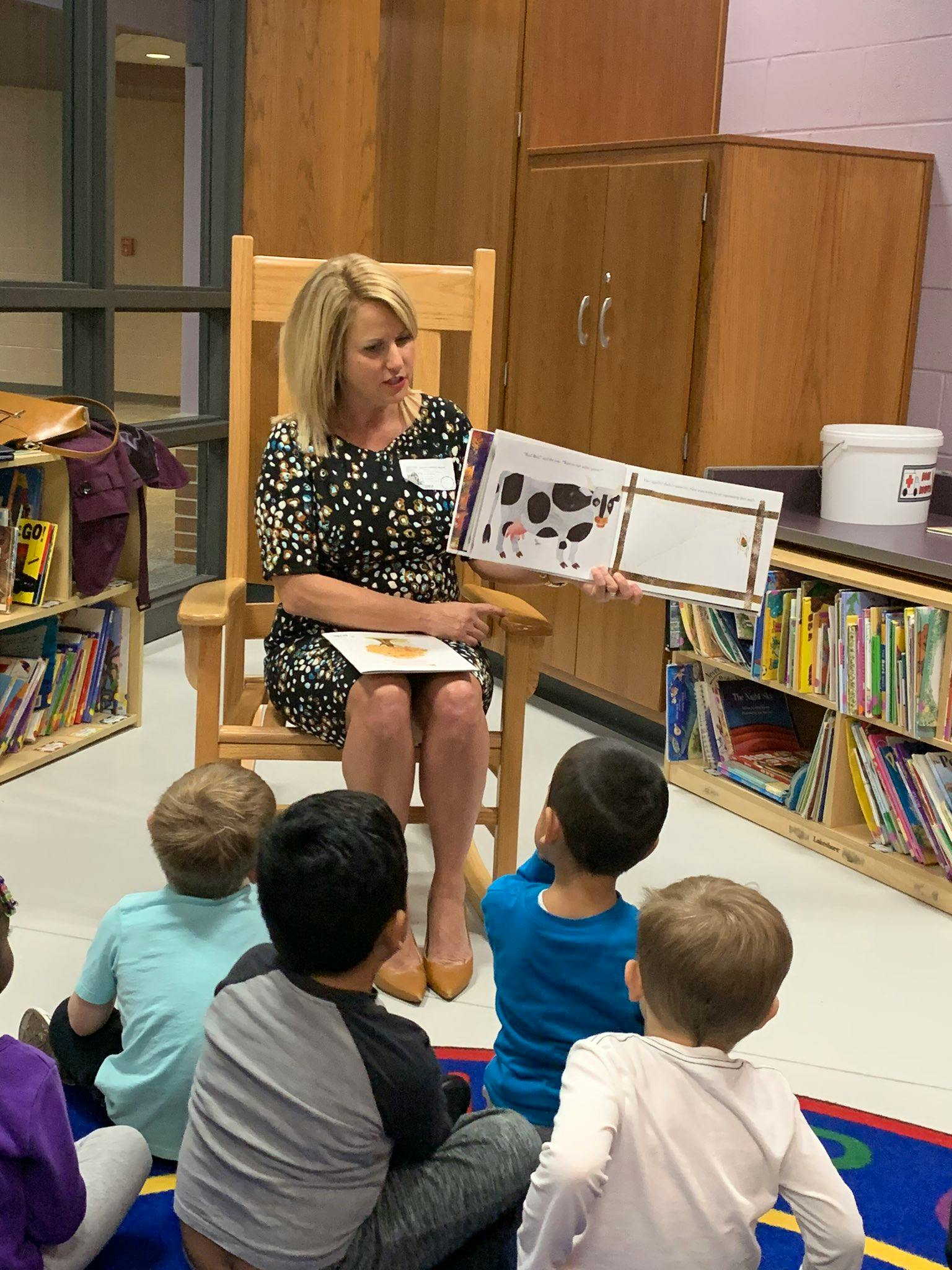 Person reading a book to children in a classroom