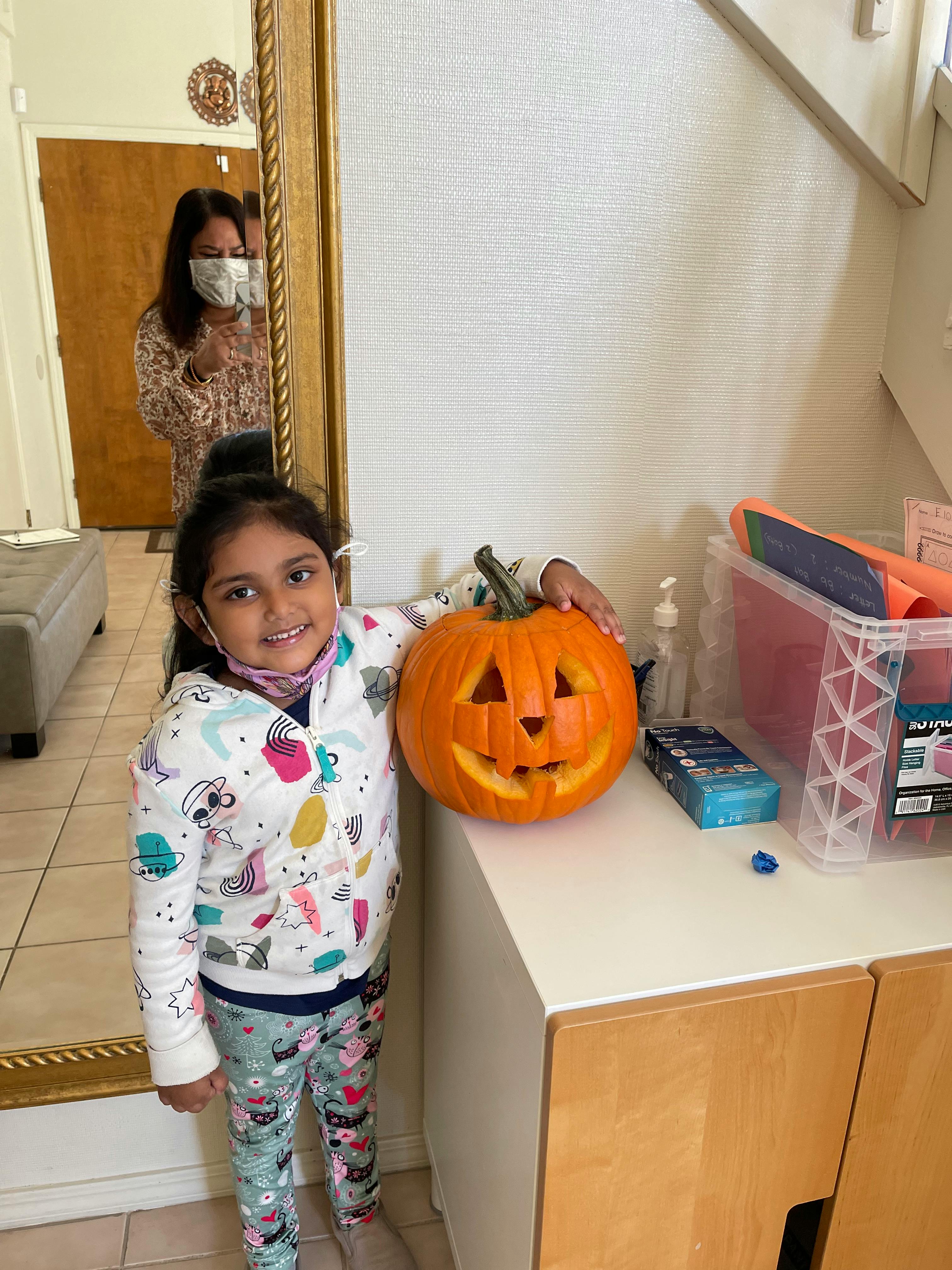 Child standing next to a carved pumpkin