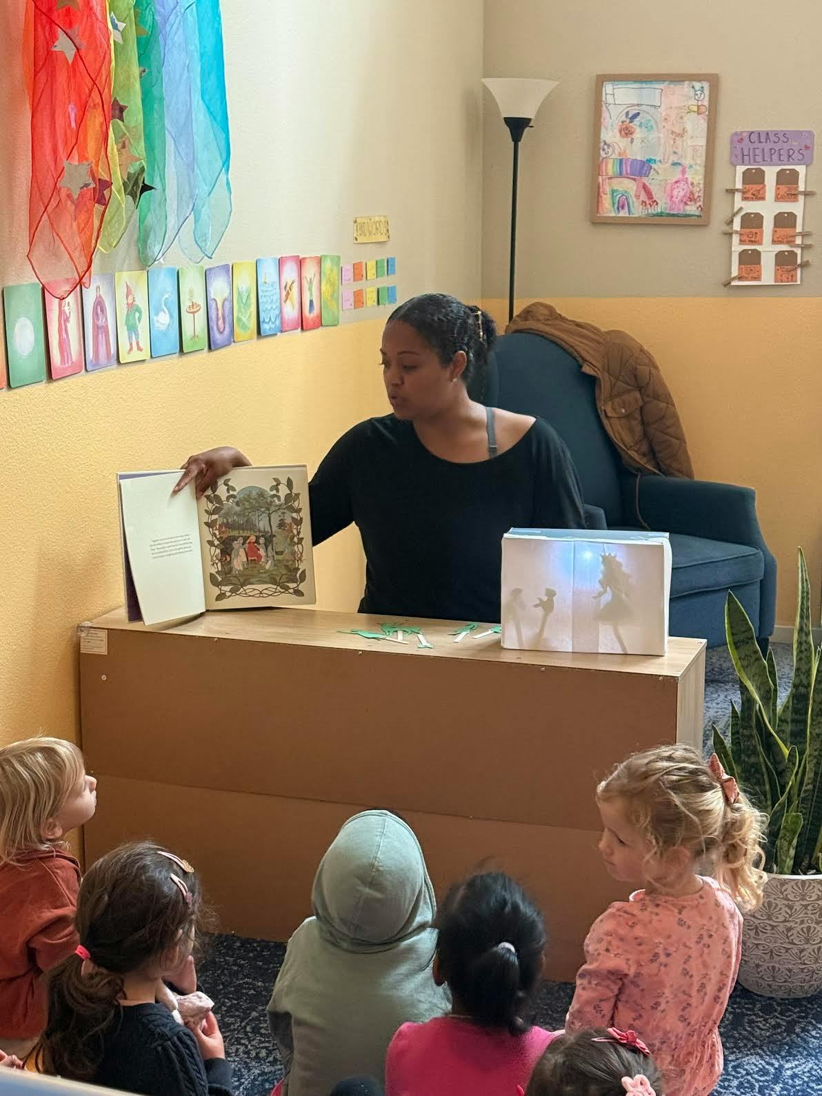 Person reading a book to a group of children in a classroom