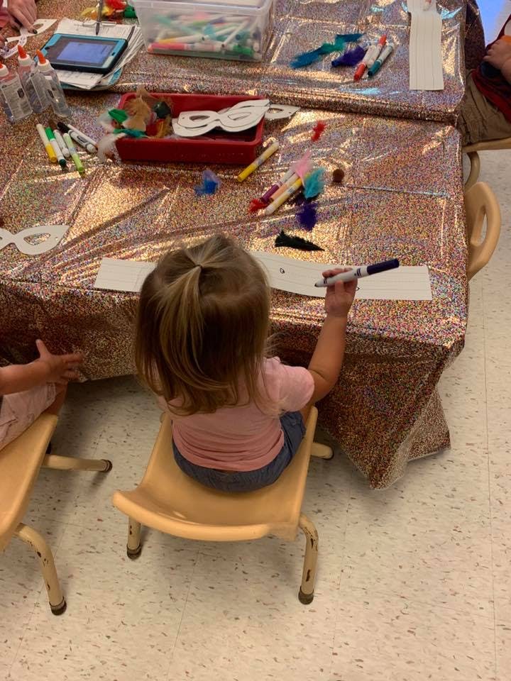 Child sitting at a table drawing on paper with a marker