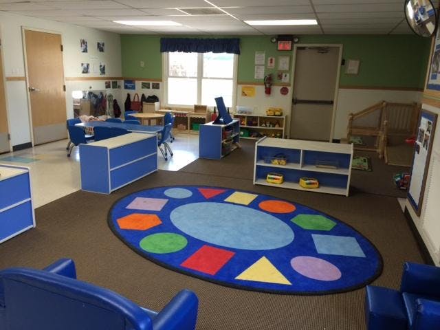 Classroom with blue furniture and a rug with colorful shapes