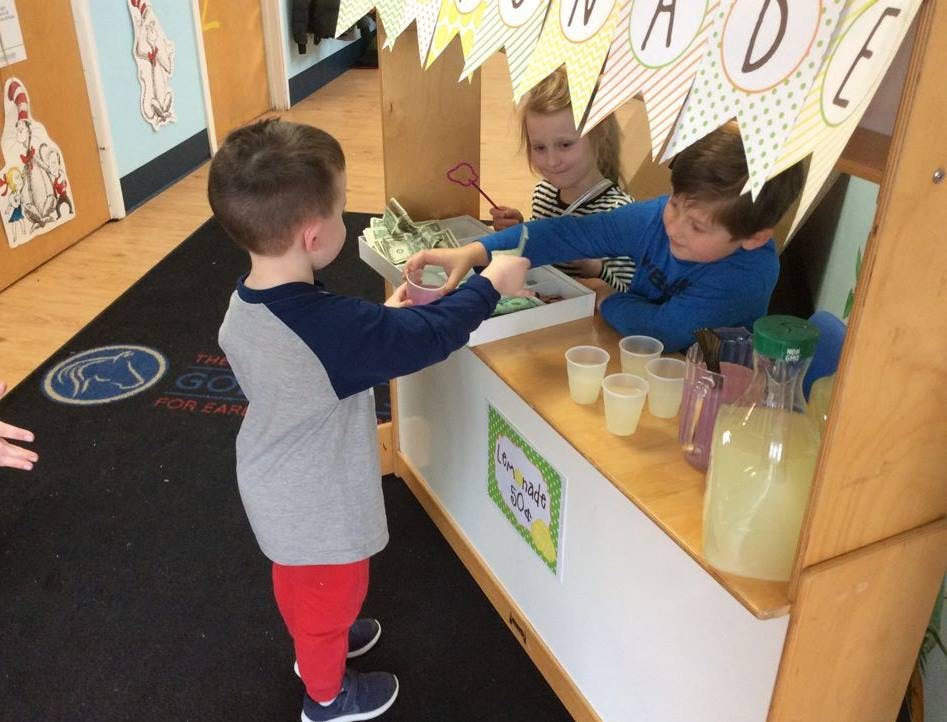 Child buying a drink from another child at a play stand