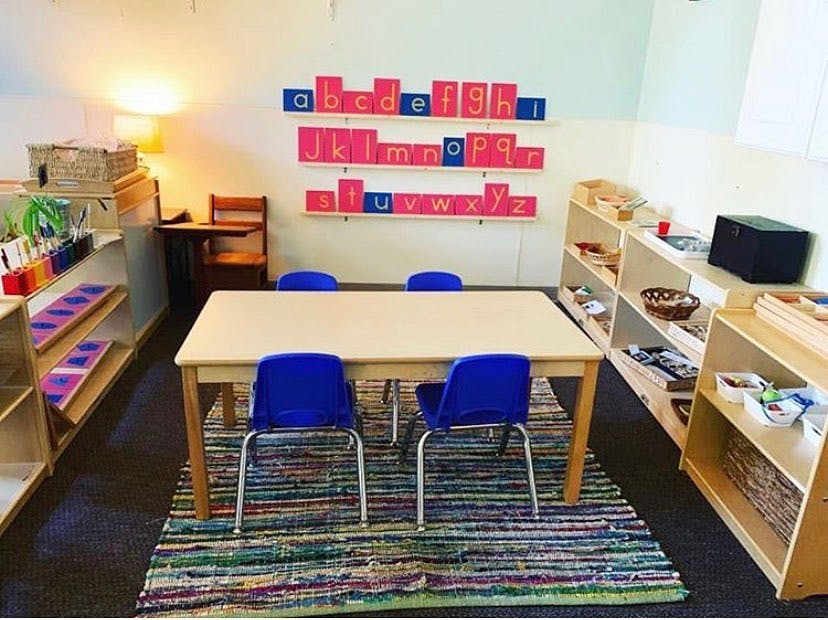 Classroom with small table and chairs, shelves, and alphabet letters on wall