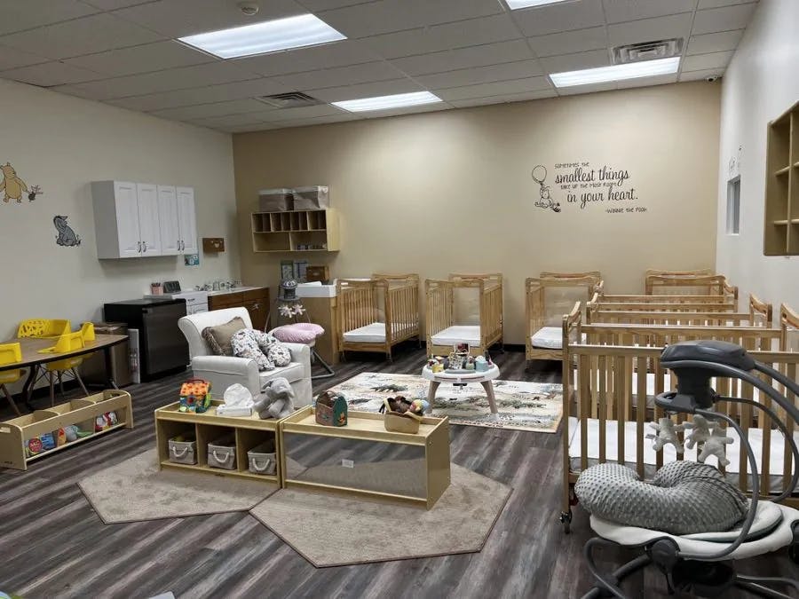 Nursery room with multiple cribs, a changing table, and a small play area