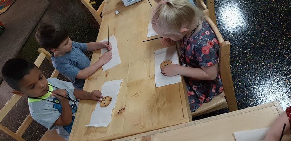 Three children drawing at a table