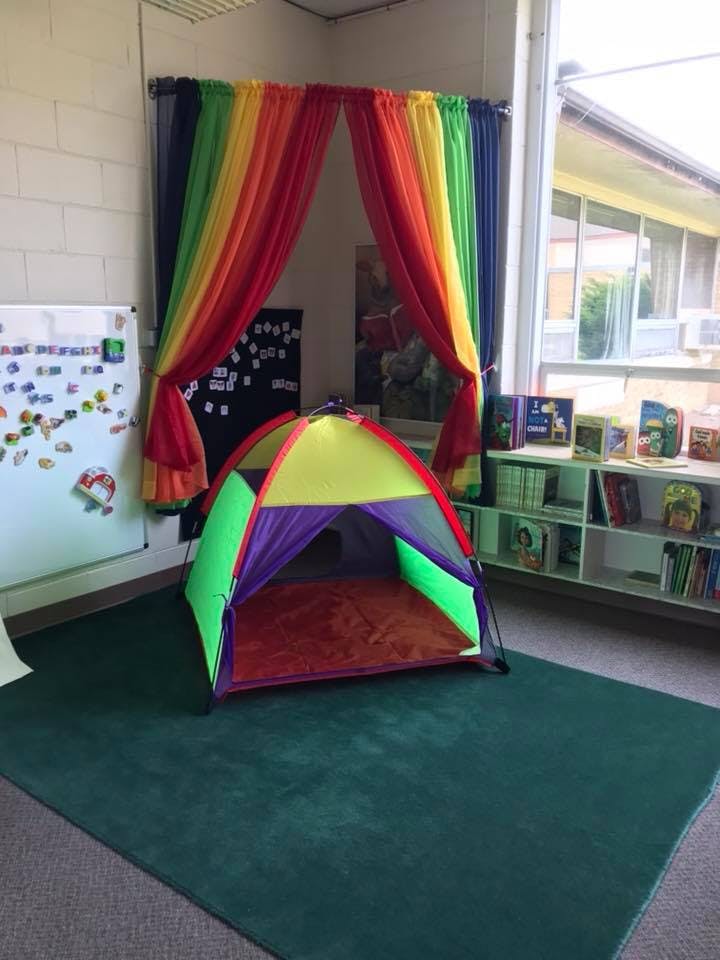 Colorful play tent on a green rug in a classroom