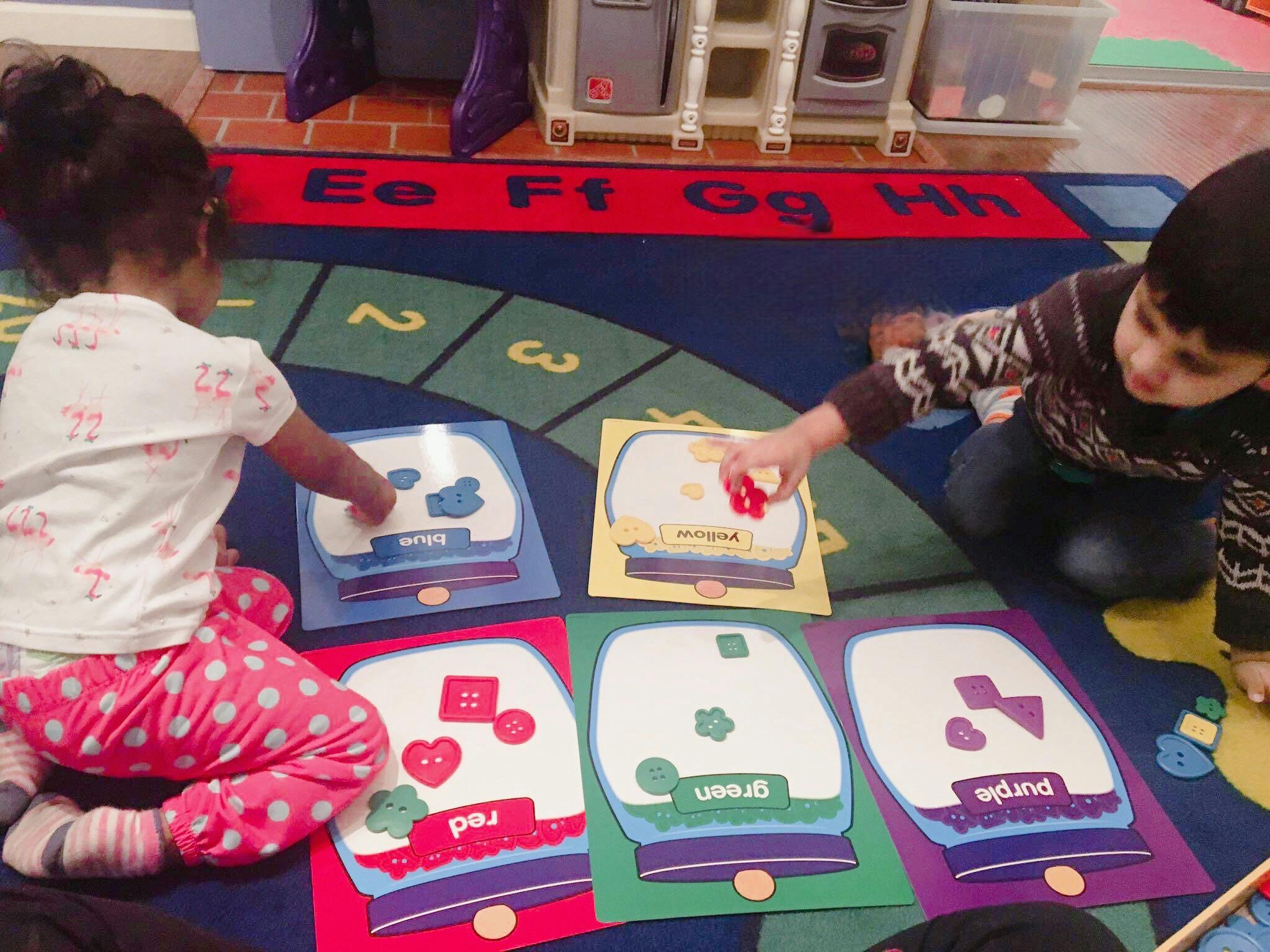 Two children playing with learning cards on a rug