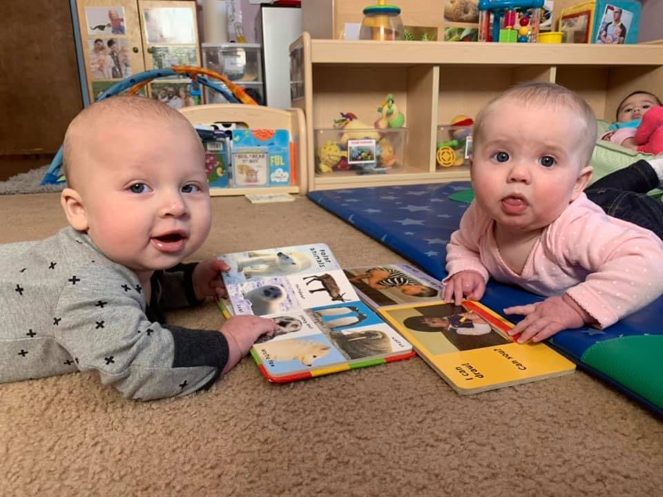 Two babies on the floor with board books