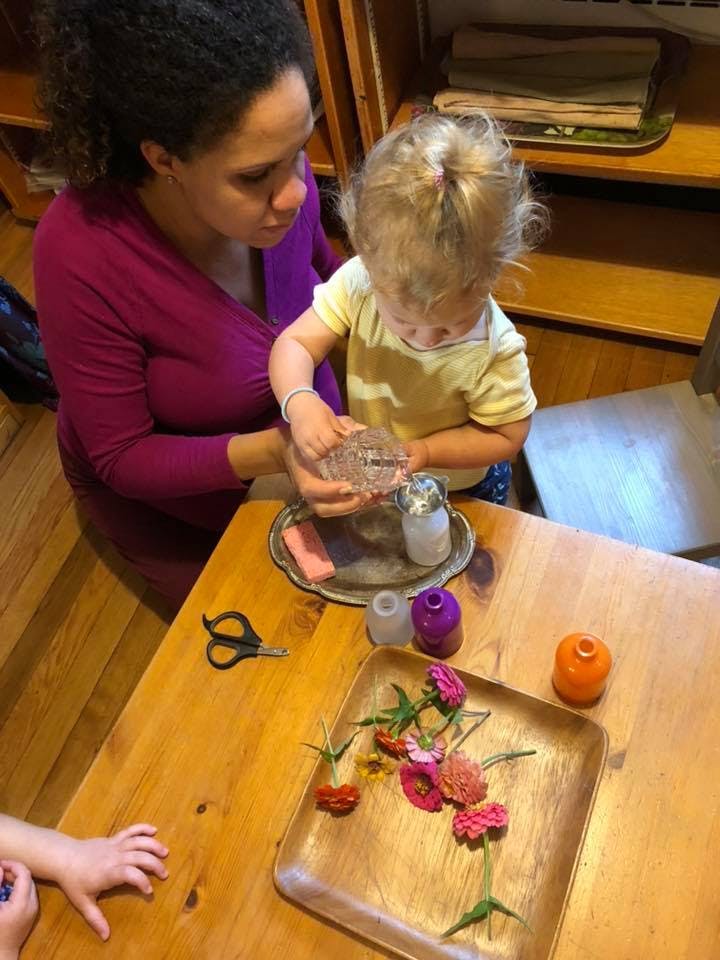 Person and child pouring water from a glass container