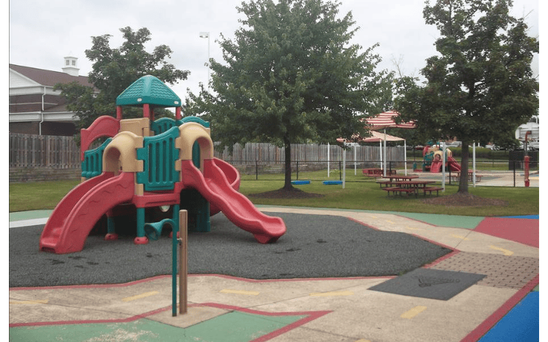 A colorful playground with slides and other play equipment on a paved surface