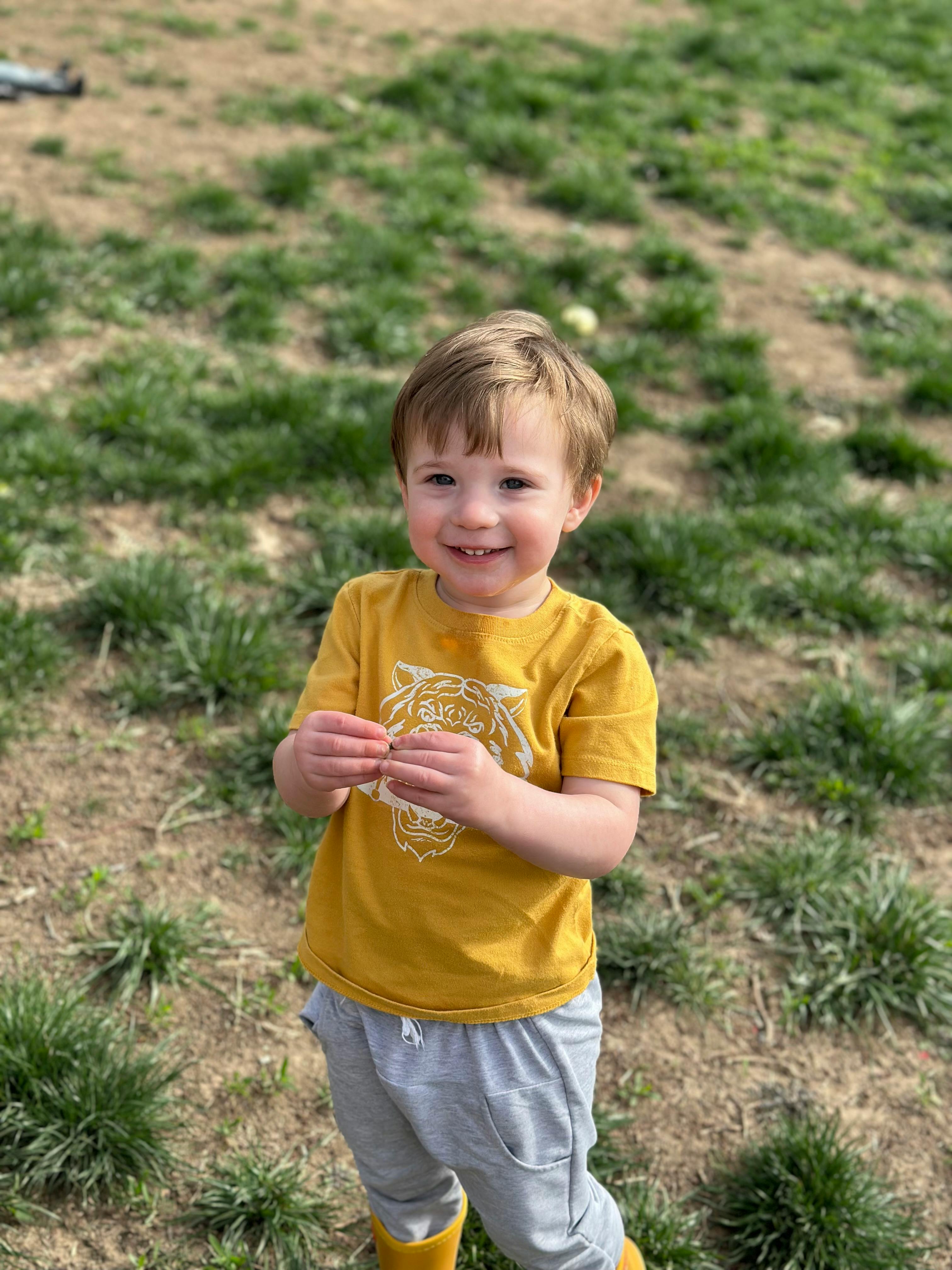Child in a yellow shirt holding something small in their hands