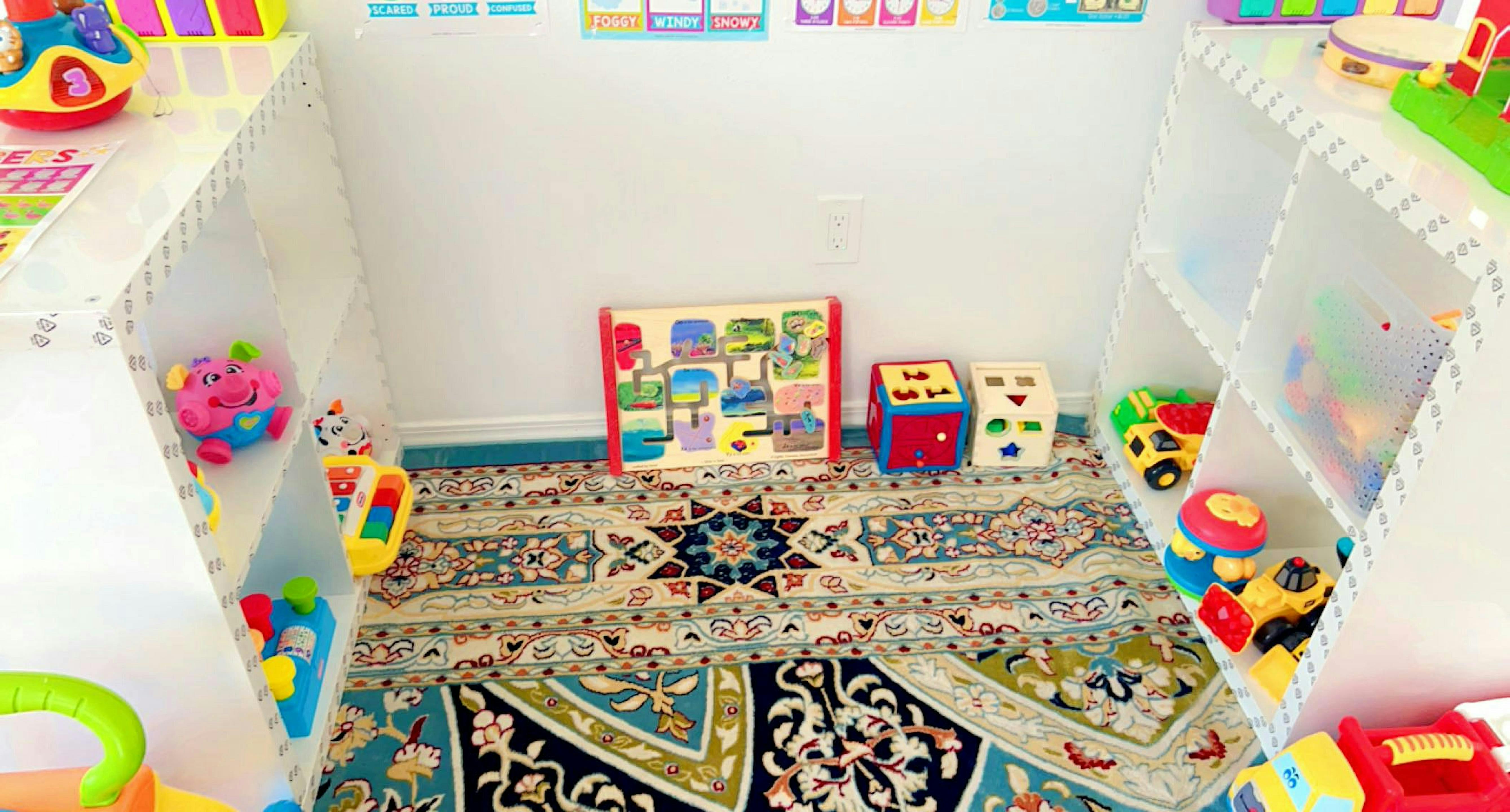 Play area with a patterned rug and shelves filled with toys