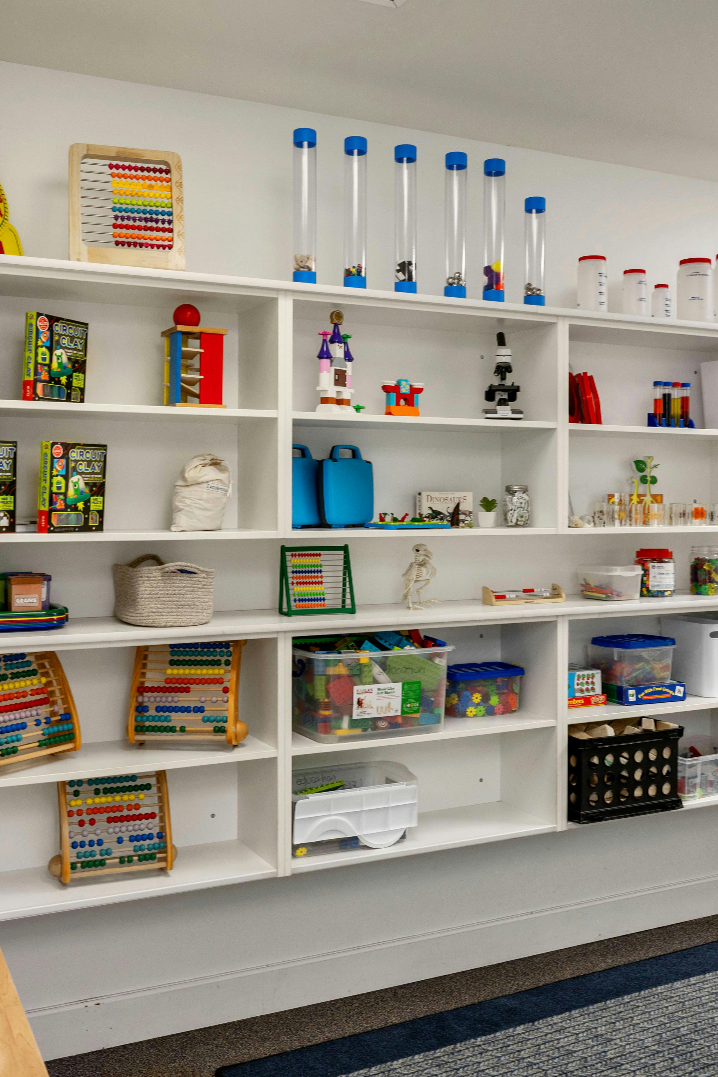 white shelves filled with various educational toys, abacuses, and science tools
