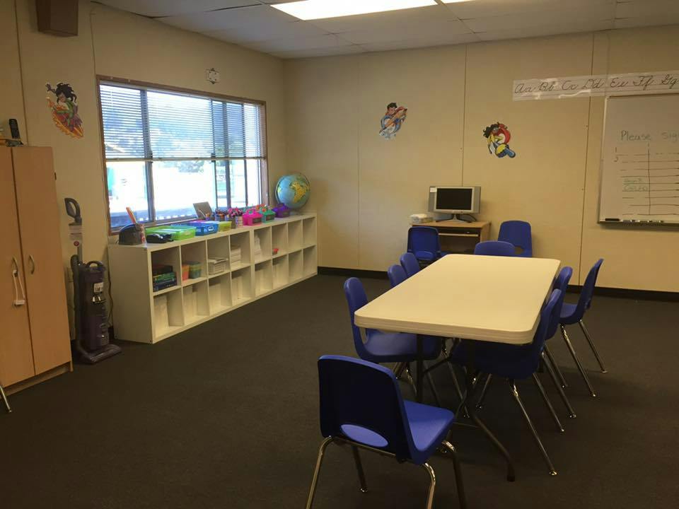 Classroom with a table and chairs, storage shelves, and a window