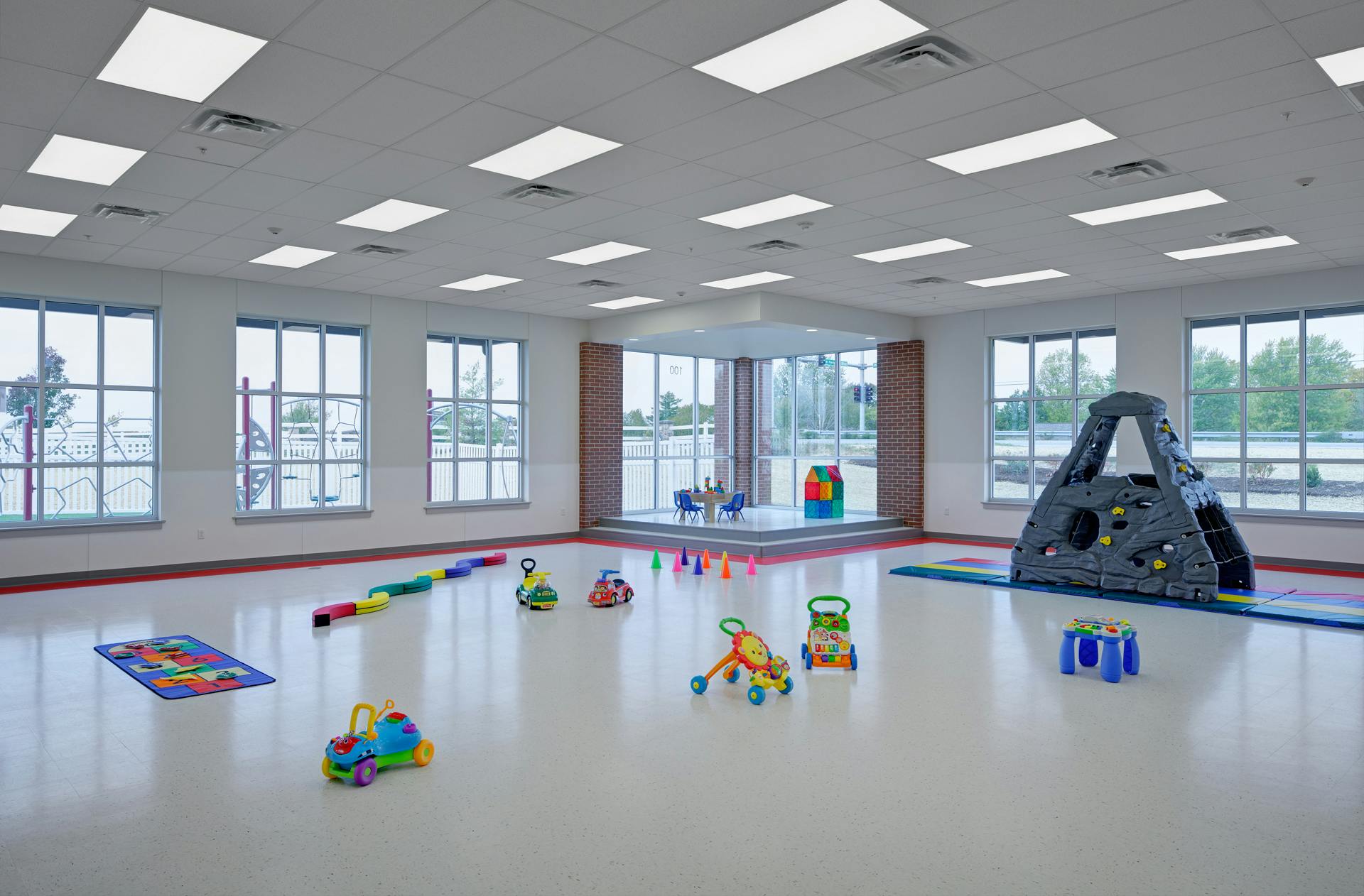 Empty playroom with various toys and a climbing structure